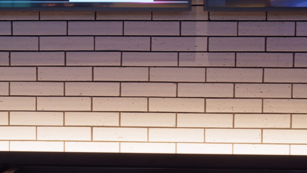 Close-up of a white glazed brick or rectangular tile wall with subtle color variations and horizontal lines.