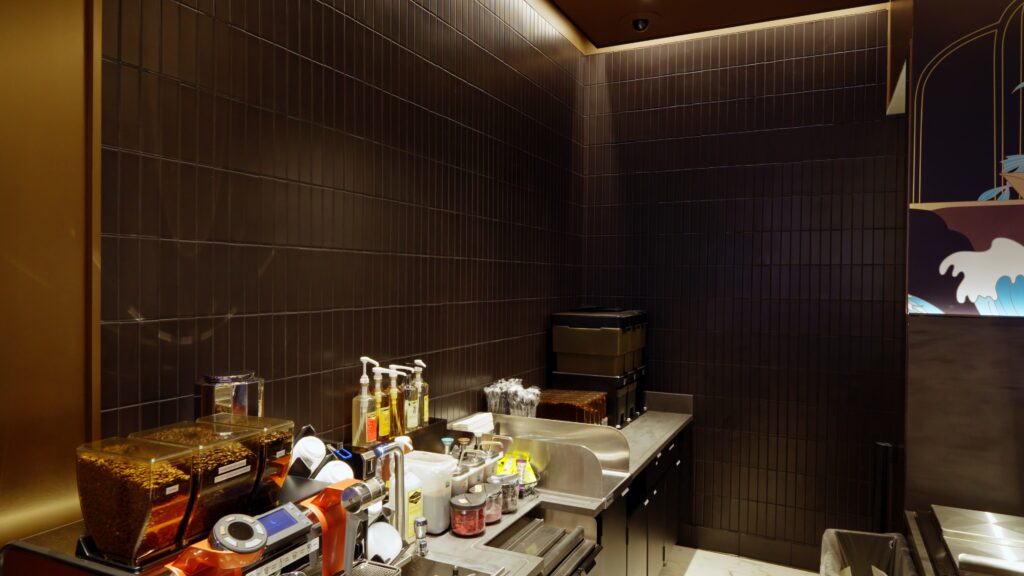 Modern coffee bar area featuring dark, vertical subway tiles on the back wall, complementing the sleek countertop and equipment.