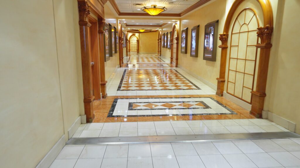 Long hotel hallway with a vibrant patterned tile flooring design and decorative borders, showcasing elegant commercial flooring.