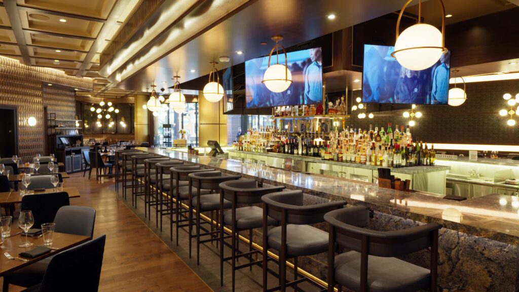 Long, contemporary bar with a large, textured stone countertop, perfect for commercial stone and granite installations.
