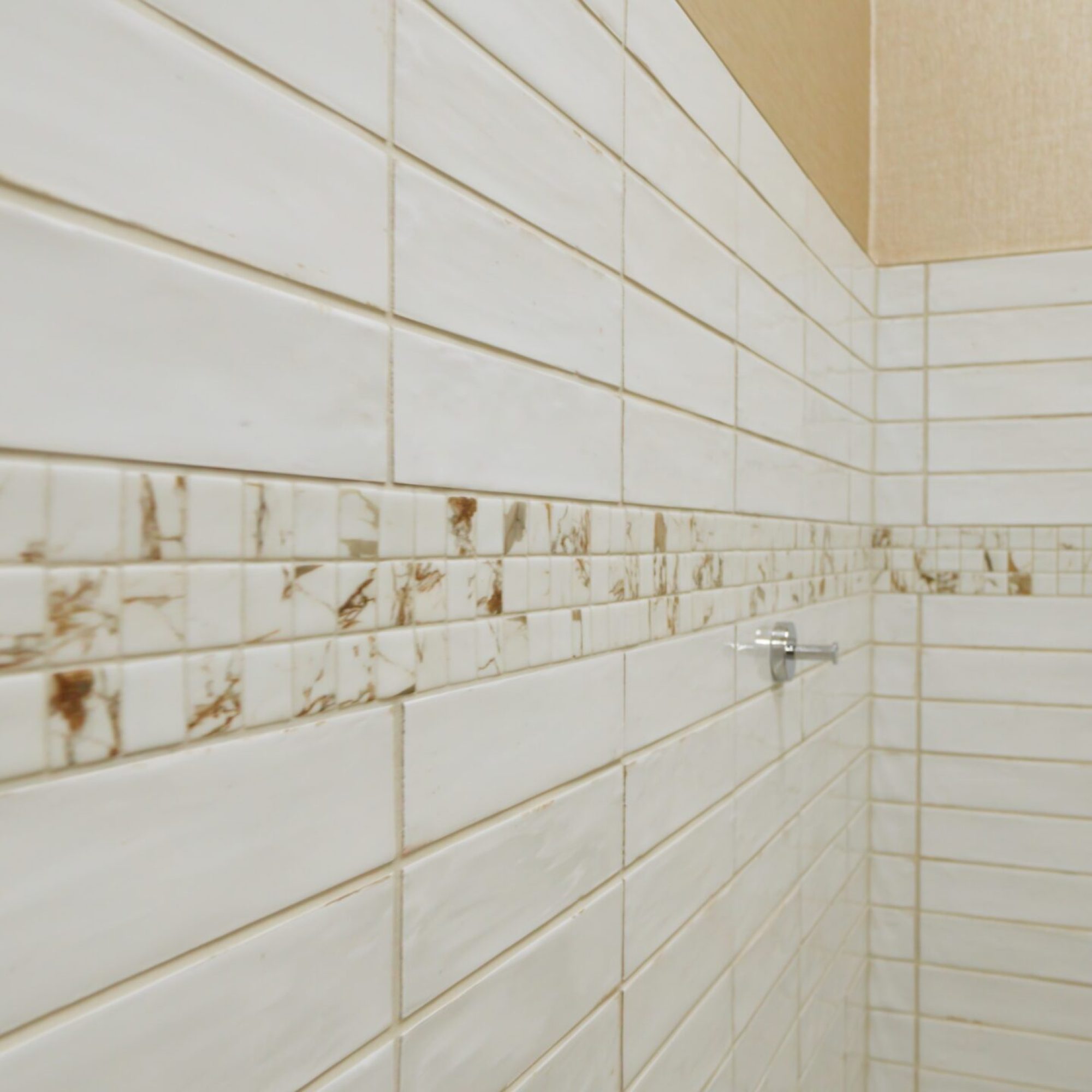 Tile wall with a decorative marble accent band, showcasing a finished tile installation